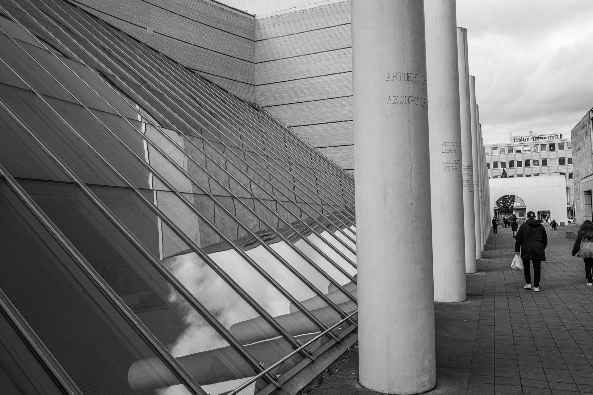 auf den Stelen, die sich auch im schrägen Fenster des Gebäudes waagrecht spiegeln sind die Menschenrechte in Stein gehauen